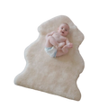 Baby lying on a beige Australian sheepskin wool rug against a white background